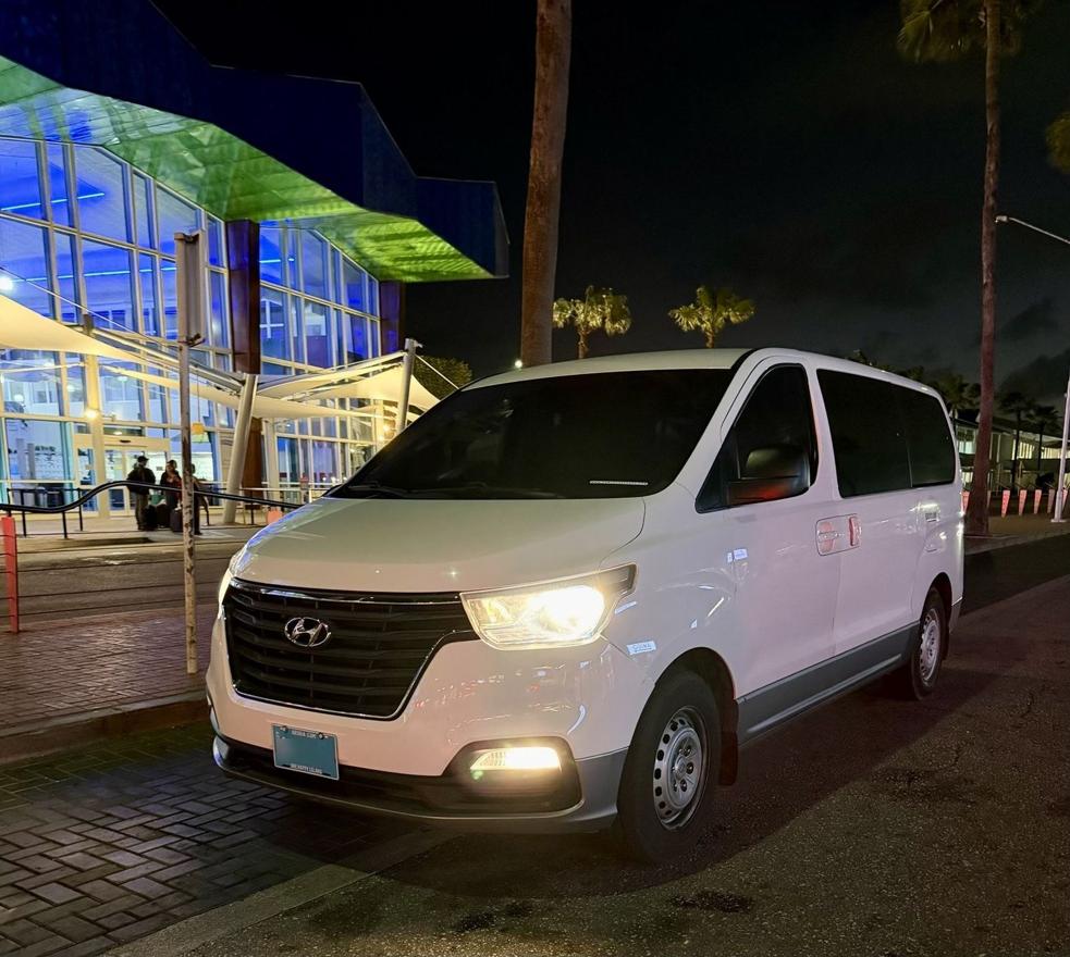 SupAce Transfers Hyundai H-1 private airport transfer van at Queen Beatrix International Airport arrivals curb in Aruba at night
